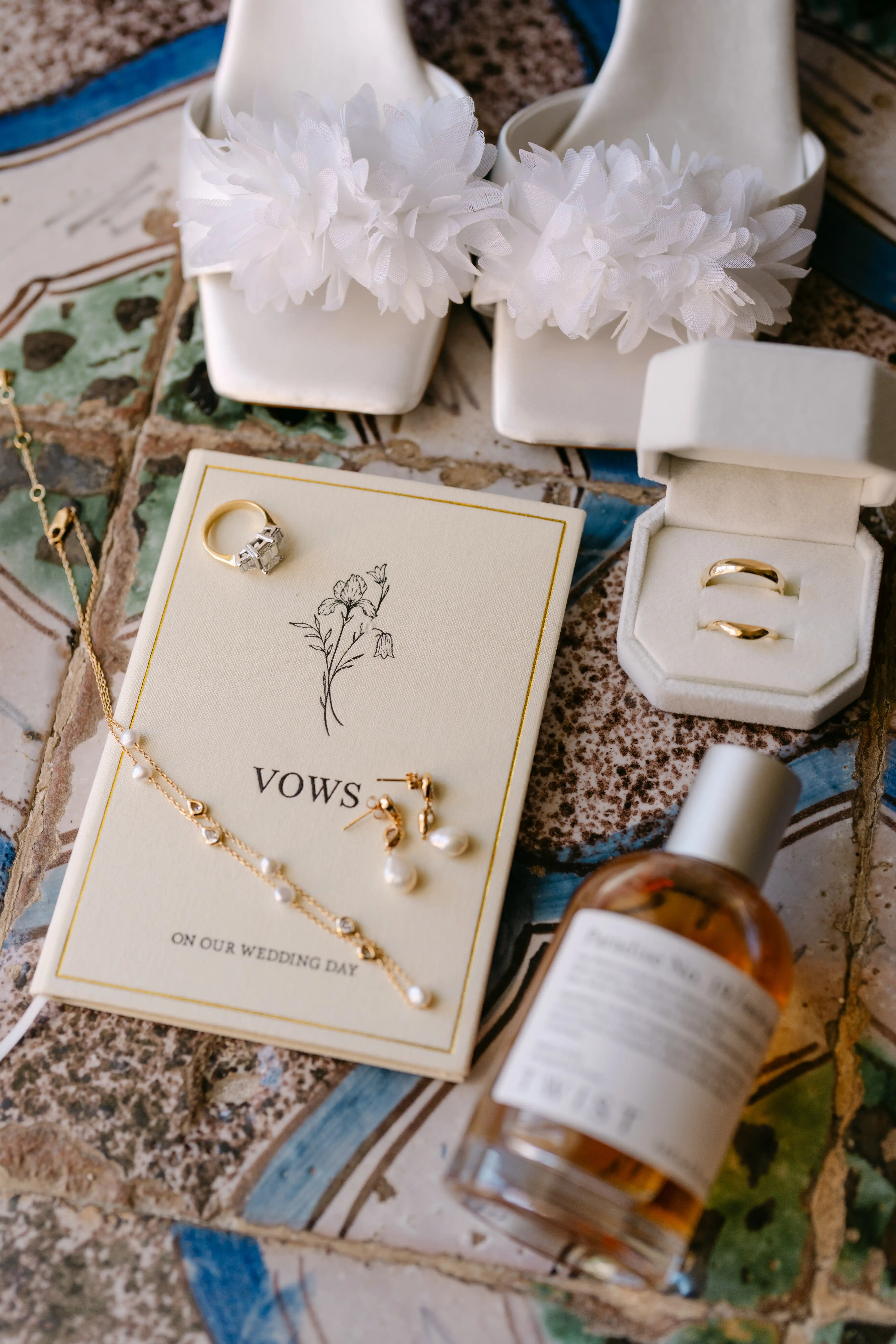 Bridal details with wedding rings, vows, perfume and elegant white shoes on Sicilian ceramic tiles